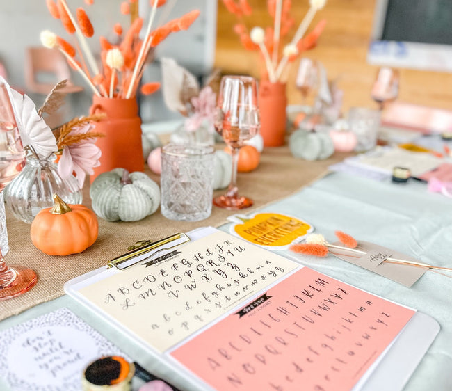 photo of calligraphy setup on a table with small pumpkin centerpieces