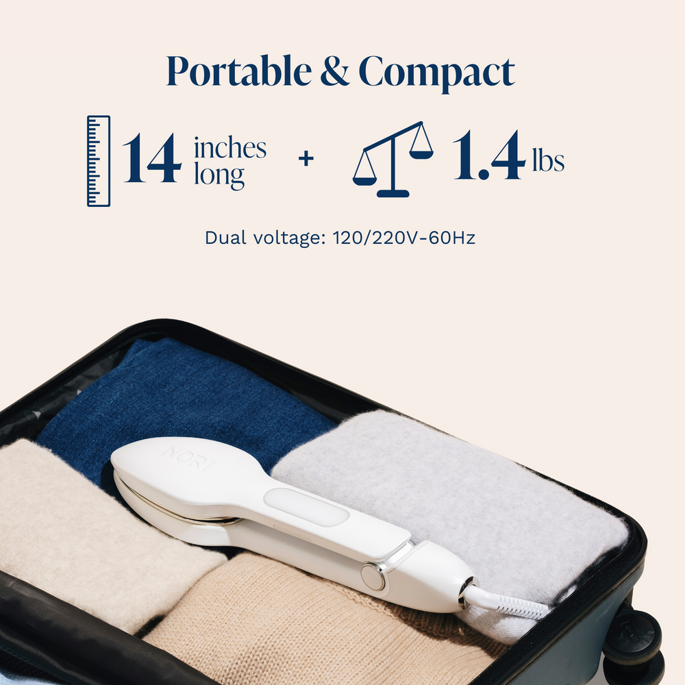 A compact hairdryer fits in a suitcase with neatly folded clothes, alongside a Nori Press Steam Iron by Nori Inc. At 14 inches and weighing 1.4 lbs, the dryer provides dual voltage (120/220V-60Hz) for global use.