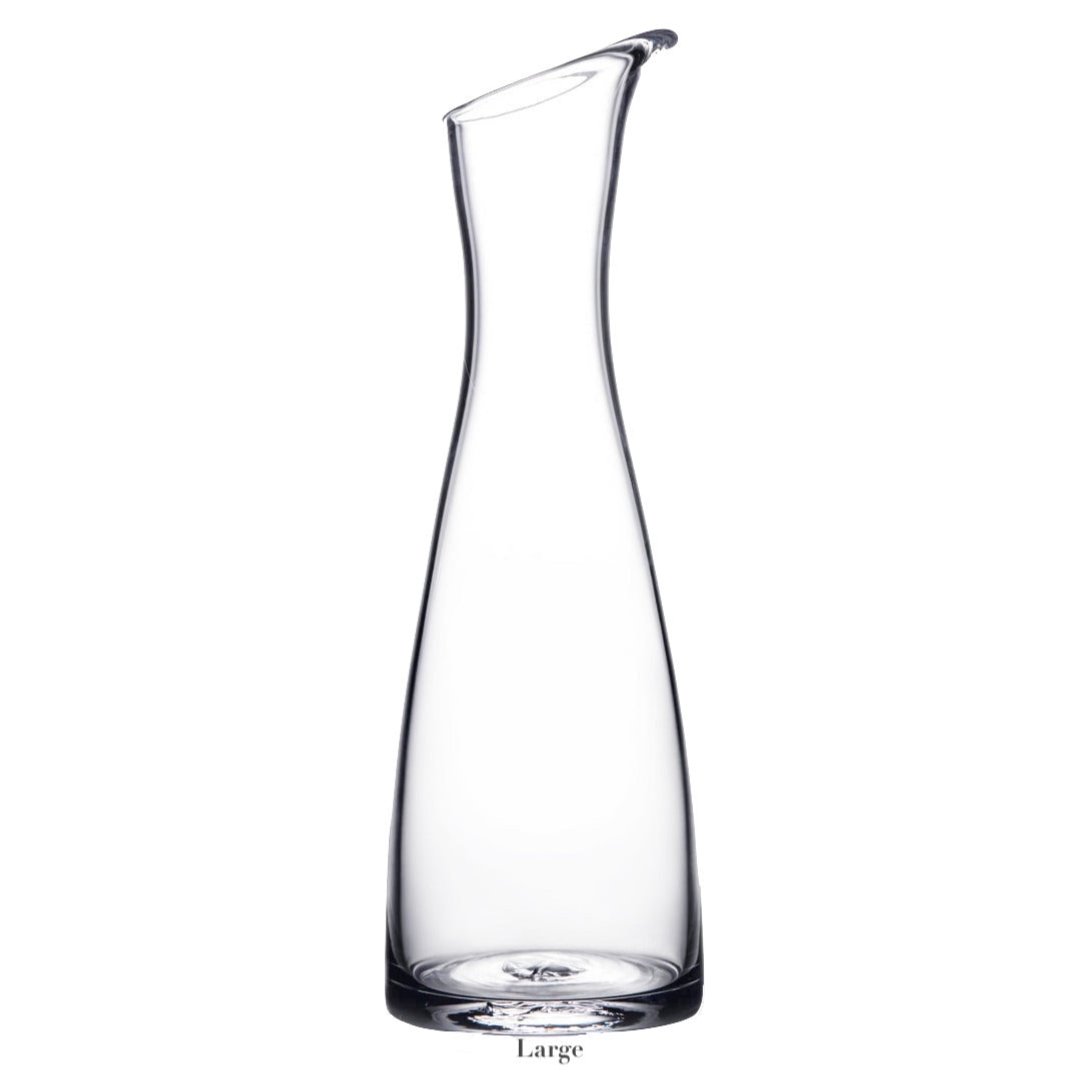 The Simon Pearce Barre Carafe Collection features a tall, clear carafe with a narrow neck and angled spout, shown on a plain white background.