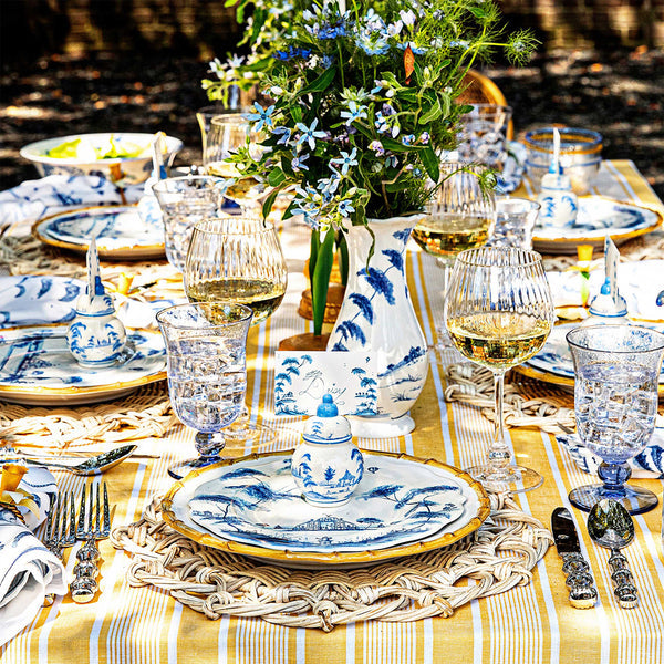 A table set outdoors with Delft Blue china, glassware, silverware, flowers, a yellow striped cloth, and Juliska Country Estate Place Card Holders as elegant accents for each guest.