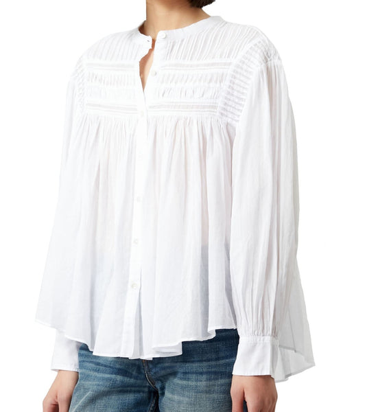 A person wearing an Isabel Marant Plalia Top, a white cotton voile top with detailed embroidery on the chest, long sleeves, paired with blue denim jeans. The image shows only the torso and does not include the person's head.