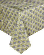 A rectangular table is set with artisanal tableware and the Lily Table Linen Collection by SLOANE BY HAND, featuring a green fabric with a repeating blue and white floral design.