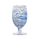 The Juliska Puro Marbled Drinkware Collection goblet features swirling blue and white patterns on a clear stem, reminiscent of seaglass hues, and is displayed against a plain white background.