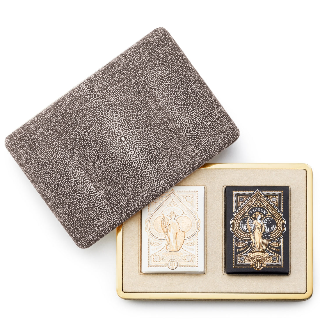 The Aerin Chocolate Shagreen Card Set features a textured case with a suede-lined beige tray holding two decorative decks—one white and gold, the other black and gold—partially displayed with the lid removed.