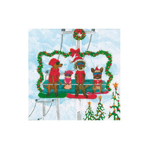 Four dogs in winter wear sit on a garland-adorned ski lift with snowy mountains behind—ideal for festive gatherings with Caspari’s Alpine Pets Cocktail Napkin.