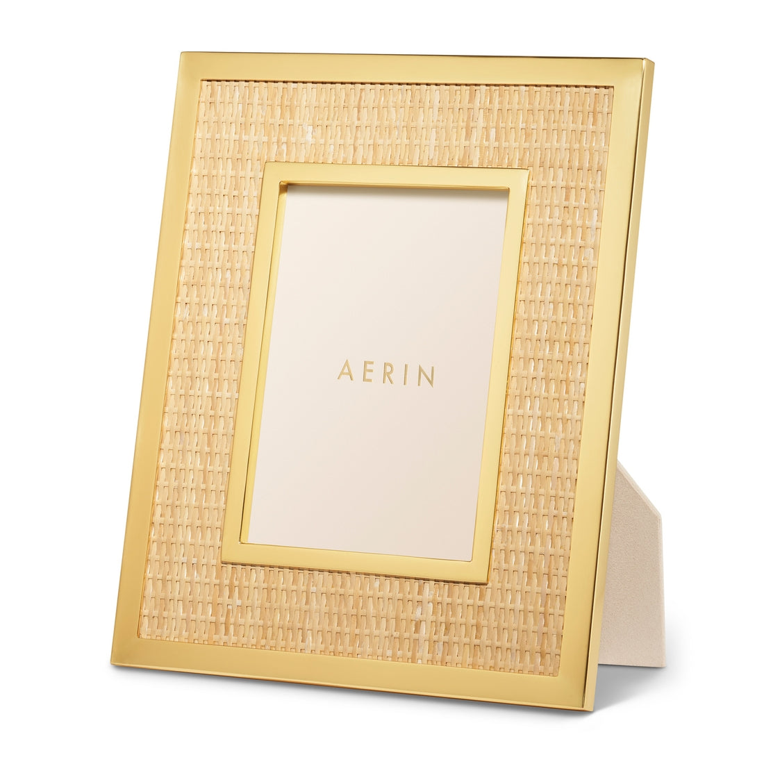 The Colette Cane Frame by Aerin showcases organic elegance with its woven rattan texture and gold brass frame, displaying a card labeled "AERIN" on a beige surface.
