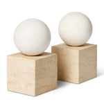 The Odette Bookend Set by Aerin features two white spheres atop beige marble cubes with natural veining, arranged side by side for a modernist touch—an elegant geometric design perfect as marble bookends.