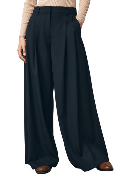 Woman wearing TWP Didi Pant high-waisted black wide-leg trousers and brown shoes.