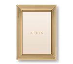 A gold rectangular photo holder from the Alessio Frame Collection by Aerin, this frame features a reeded design with layered ridges and displays a blank insert printed with "AERIN"—ideal for showcasing elegant photographs.