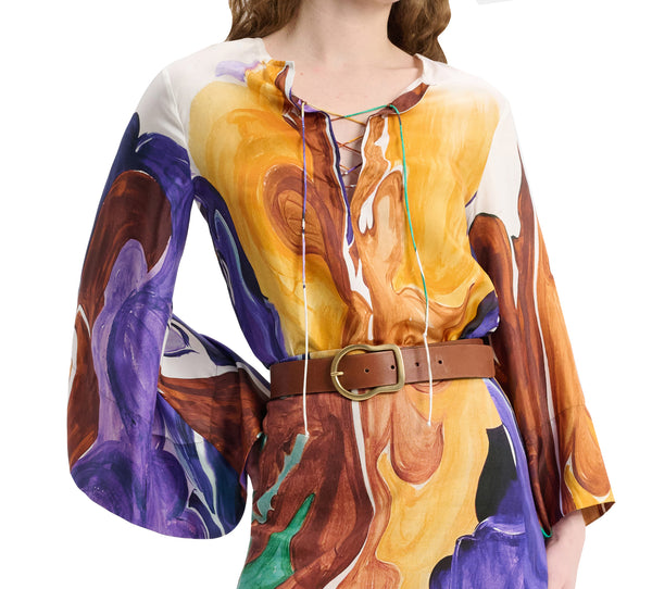 A woman wearing a Dorothee Schumacher Rainbow Dreams Blouse with abstract designs and a brown belt.
