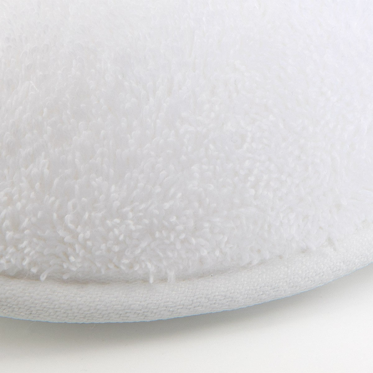 Close-up view of the edge of Etoile Blanc Slippers by Yves Delorme, featuring ultra-absorbent, white long-staple cotton fabric on a white background.