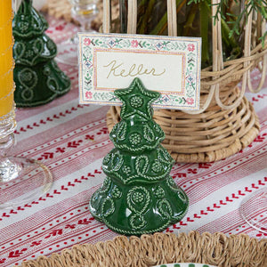 The Juliska Berry & Thread Basil Tree Place Card Holder Set adds festive charm to your table, displaying name cards atop a red and white tablecloth for a cheerful holiday setting.