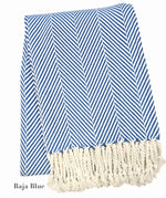 The Nantucket Herringbone Throw Collection by A Soft Idea features blue and white stripes with diagonal lines and hand-knotted fringe tassels on one end.