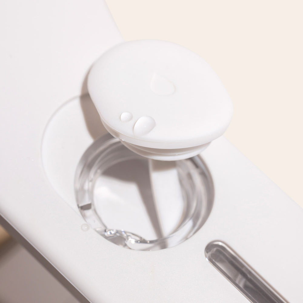 Close-up of the white round cap with water droplets on the Nori Press Steam Iron by Nori Inc, showcasing a circular opening and a narrow slot.