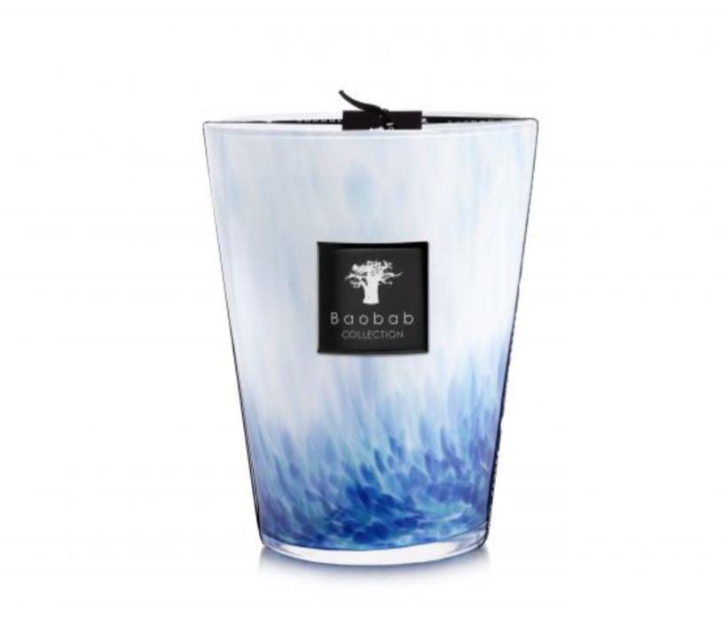 A tall, decorative scented candle featuring a blue and white gradient design. The label reads "Baobab Collection Eden Seaside Candle," evoking the rich warmth of amber intertwined with hints of vetiver.