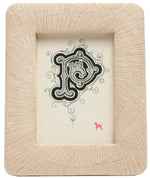 A decorative letter "P" in black ink on white paper is displayed in Pigeon & Poodle’s Ancona Frame Collection, featuring a textured, light-toned rectangular frame and accented with a small red animal at the bottom right for creative flair.