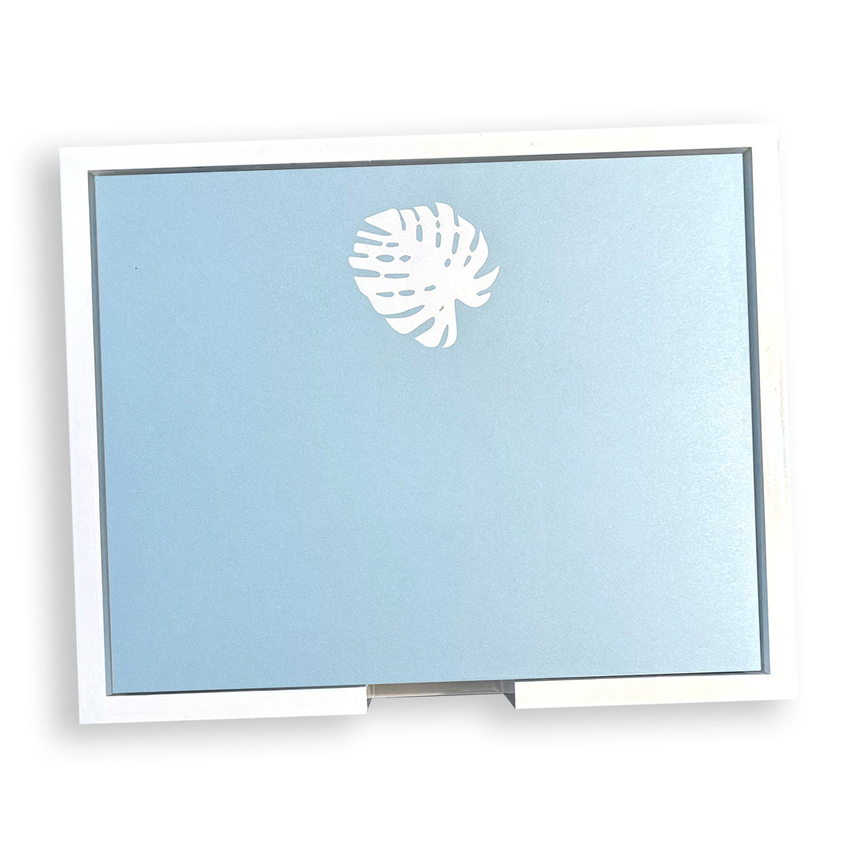 A rectangular light blue card from the Large Blue Note Pad Collection by Black Ink, featuring a white monstera leaf at the top center and a white border.