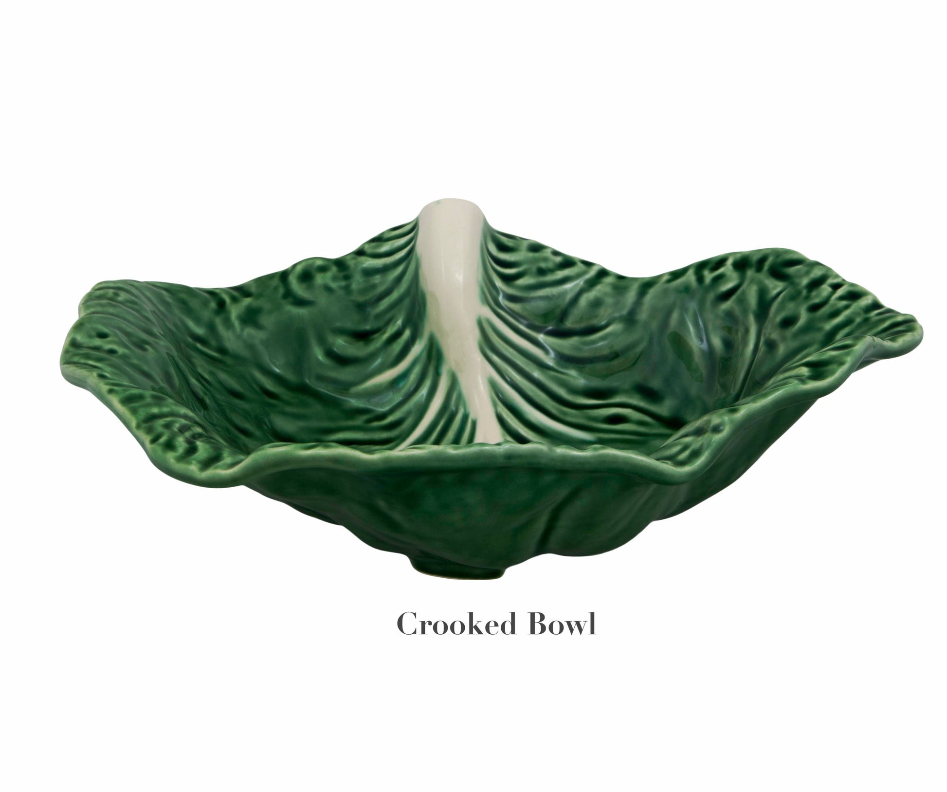 The Bordallo Pinheiro Cabbage Leaf Green Collection features a ceramic bowl in a cabbage-like design with a green leaf shape, wavy edge, and white center accent. Known as the "Crooked Bowl," this piece, made in Portugal by Bordallo Pinheiro, showcases charming handmade artistry.