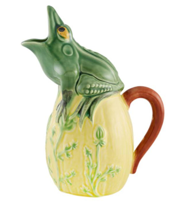 The Hive Frog Pitcher is a whimsical ceramic piece featuring a frog perched on a yellow base with a brown handle and vibrant green plant designs.