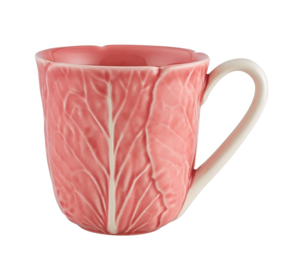 The Pink Cabbage Leaf Dinnerware and Serveware Collection by Hive features a pink ceramic mug with a handle, adorned with a leaf-textured pattern inspired by Raphael Bordallo Pinheiro’s iconic designs.