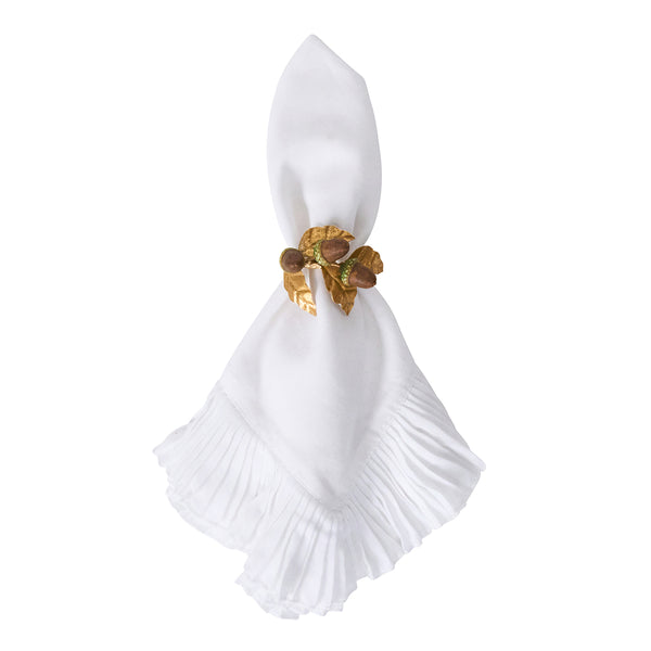 A white cloth napkin with pleated edges is secured by a gold napkin ring featuring a leaf and acorn design from the Juliska Forest Walk Tabletop Collection, ideal for pairing with matching place card or candle holders.
