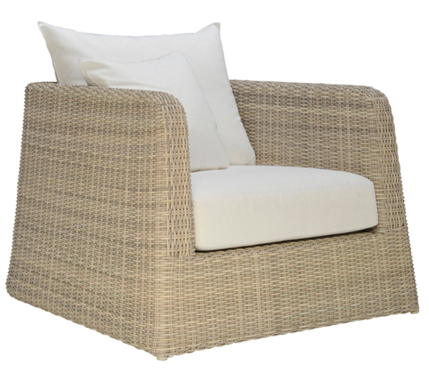 The Zeya Outdoor Lounge Chair by Janus et Cie is a weather-resistant wicker armchair with a boxy shape, white seat and back cushions, and two white throw pillows—ideal for stylish outdoor living.