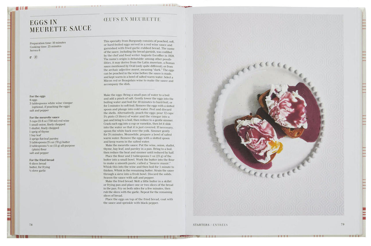 An open copy of *Classic French Recipes* by Phaidon features a recipe for eggs in Meurette sauce on the left page and a plated dish of the recipe on the right, capturing the essence of French home cooking.
