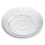 The Shell Serveware Collection by Simon Pearce features a round, clear glass plate with an embossed spiral shell design—an ideal accent for beach-themed decor or a standout summer host gift.