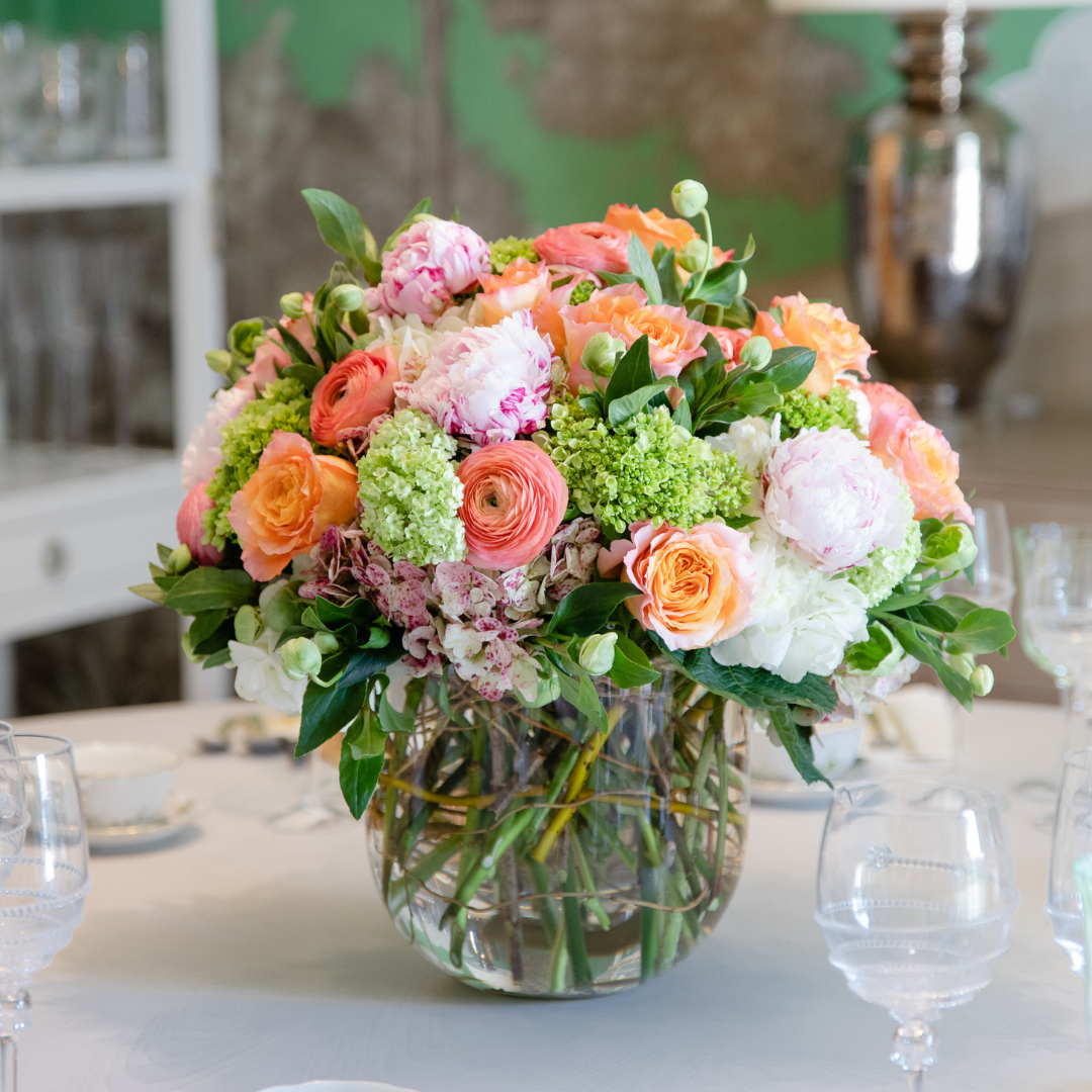 A glass vase filled with a Hive Floral Studio Live Designer's Choice Floral Arrangement on a table.
