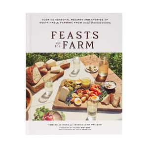 The cover of "Feasts on the Farm" by Chronicle Books shows a picnic table outdoors with bread, cheese, eggs, and fruit.