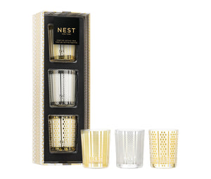 The Nest Festive Votive Trio includes birchwood pine, winter chai, and holiday votives in decorative gold, silver, and clear glass holders displayed in front of the box.