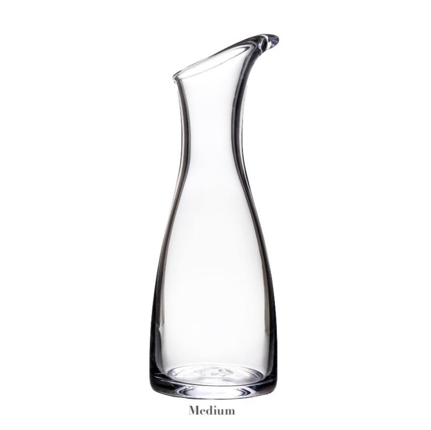A handmade glass carafe from the Barre Carafe Collection by Simon Pearce stands upright on a white background, showcasing its curved spout and narrow neck. "Medium" appears below, highlighting the collection’s signature elegance.