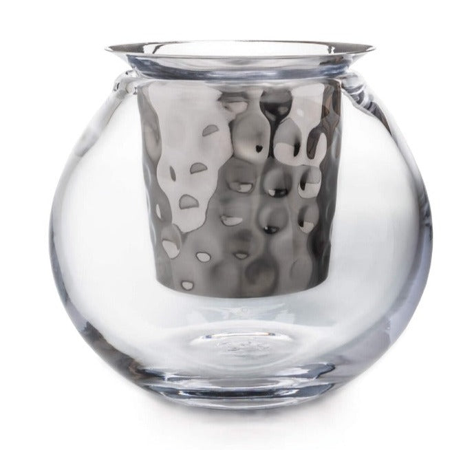 The Simon Pearce Hampton Chiller is a clear, round glass teacup crafted with handmade glassblowing techniques and features a metallic, hammered-texture infuser inside.