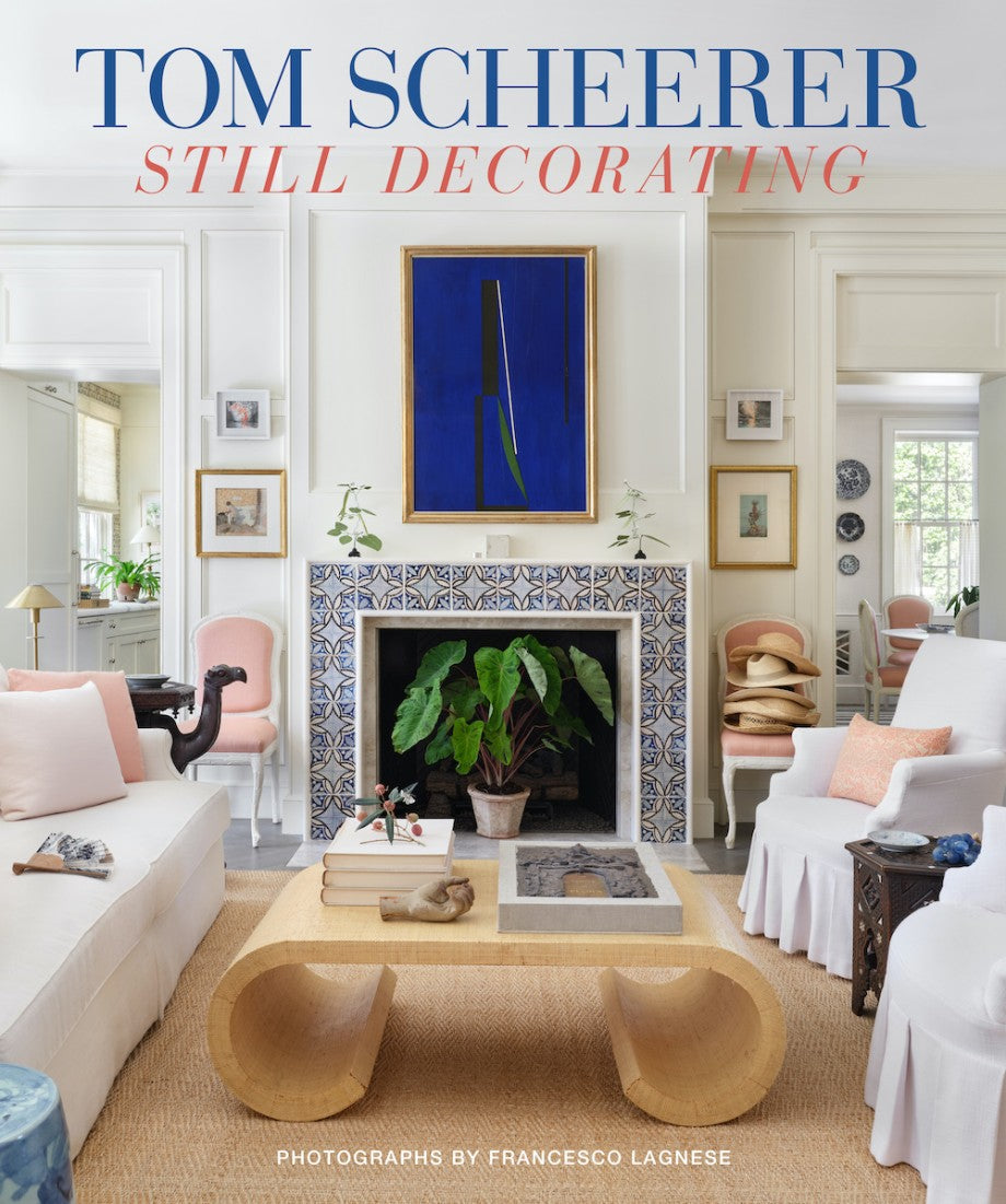 The cover of Tom Scheerer: Still Decorating by Abrams features a bright, elegant living room with white sofas, a tiled fireplace, and blue artwork above the mantel—showcasing the interior designer's refined projects.
