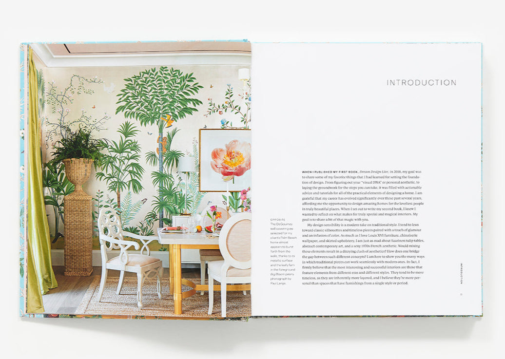 Open book displaying "The New Classic Home" by Abrams: left page shows a colorful dining room with botanical wallpaper, right page features text headed "INTRODUCTION.