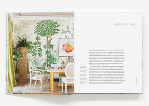 Open book displaying "The New Classic Home" by Abrams: left page shows a colorful dining room with botanical wallpaper, right page features text headed "INTRODUCTION.