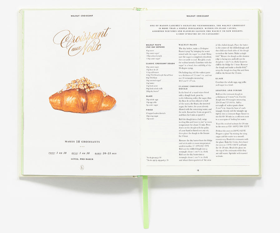 An open copy of Abrams' The Little Book of Ladurée: Patisserie shows a walnut croissant recipe, with an illustration on the left page and classic Parisian dessert ingredients and instructions on the right.