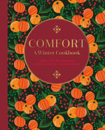 Cover of *Comfort: A Winter Cookbook* by Common Ground, showcasing a red circle with text set against an orange and green fruit pattern background, ideal for discovering Fireside Feasts.