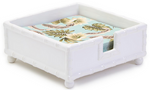 The Two's Company Faux Bamboo Dinner Napkin Holder is a white ceramic holder with a floral-patterned napkin stack inside and a bamboo-style cutout on one side for easy access.