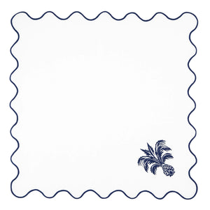 The Ananas Blue Napkin Set by Aquazzura Casa features Italian-made white linen with scallop edges, wavy navy blue trim, and an embroidered pineapple and palm leaf in one corner—perfect for adding elegance to your table.