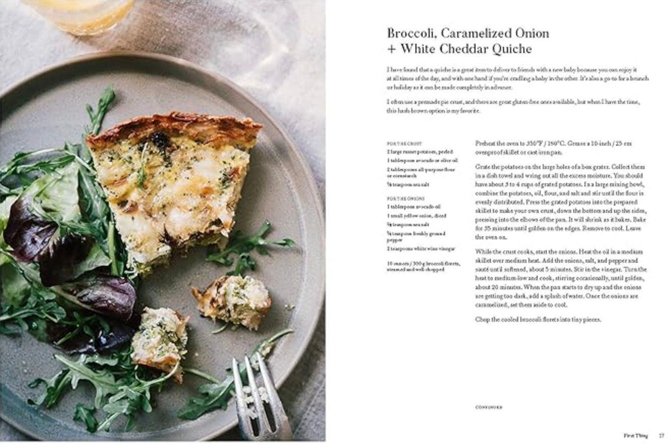 A plate of broccoli, caramelized onion, and white cheddar quiche with mixed greens sits next to a recipe text from Chronicle Books' cookbook "Around Our Table: Wholesome Recipes to Feed Your Family and Friends.