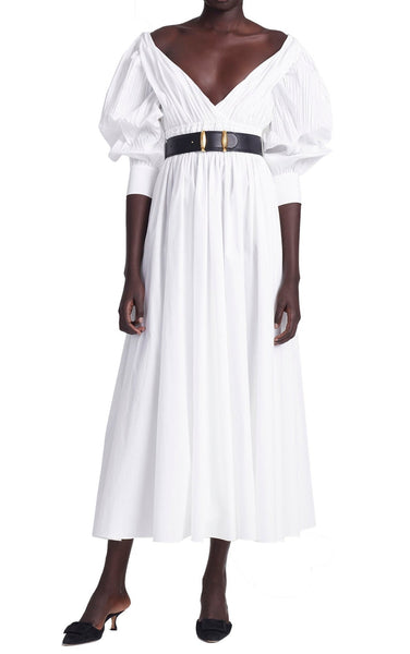 A woman wearing an Altuzarra Kathleen Optic White dress with a maxi silhouette and puff sleeves, standing against a white background.