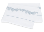 Two folded white pillowcases from the Atoll Bedding Collection by Matouk for Wedgwood, crafted of Ceylon cotton percale and featuring blue botanical embroidery along the satin stitch border.