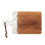 The Austin Swirled Serveware Collection by Blue Pheasant features a rectangular handcrafted wooden cutting board with a handle, a white marbled resin accent on one side, and a brown leather loop on the handle.