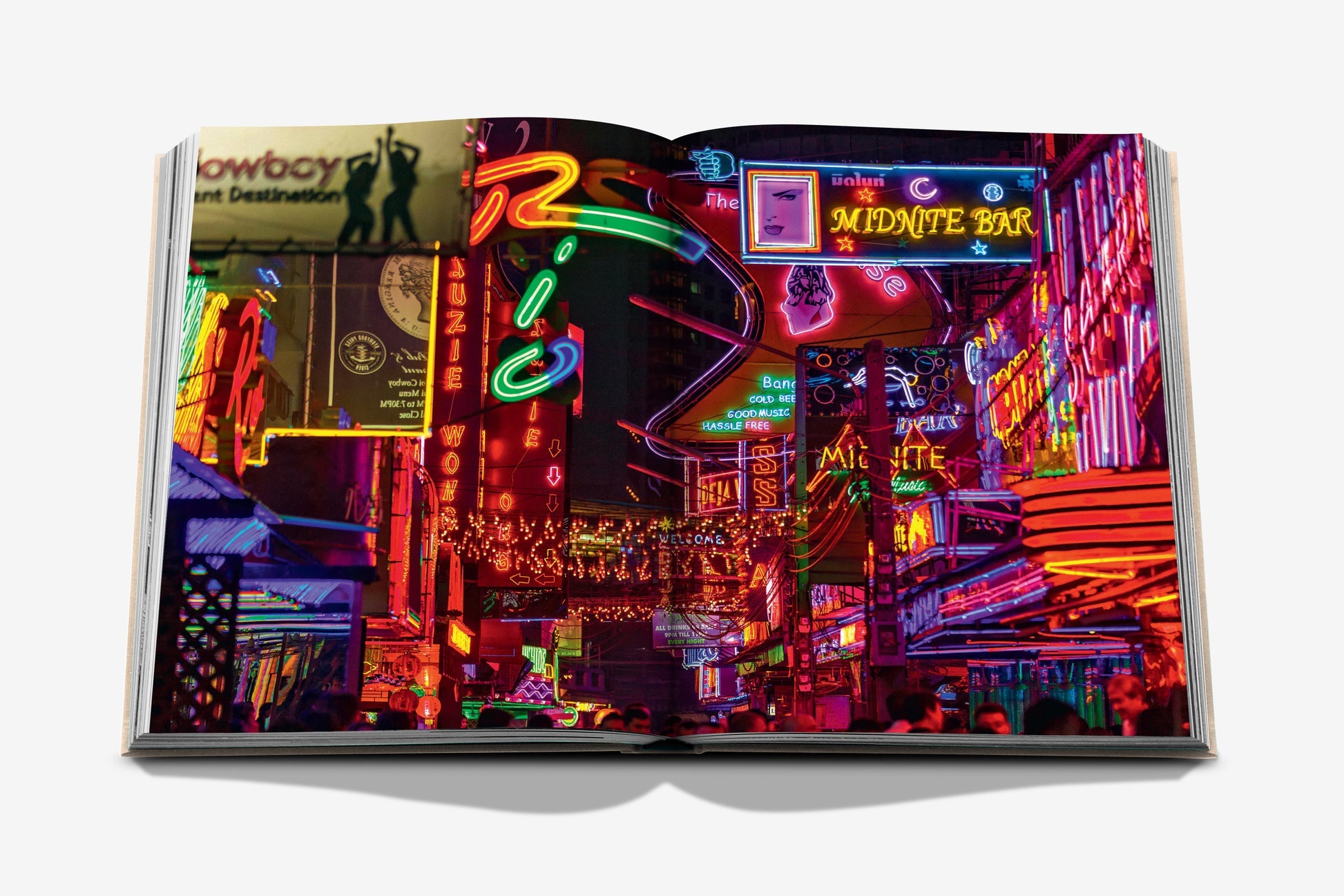 The Assouline book "Bangkok Spirit" features a vibrant street scene with colorful neon signs and lights, perfectly capturing the bustling energy of Bangkok's street-food markets.