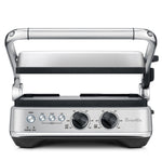 The Breville Sear & Press Grill is a stainless steel countertop grill with adjustable top lid, front control dials, and buttons, serving as a versatile panini press for delicious sandwiches and grilled foods.