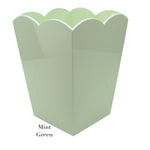 The Addison Ross Scalloped Lacquer Waste Bin Collection features a mint green container with scalloped edges and "Mint Green" elegantly printed, adding sophistication to its plain background.