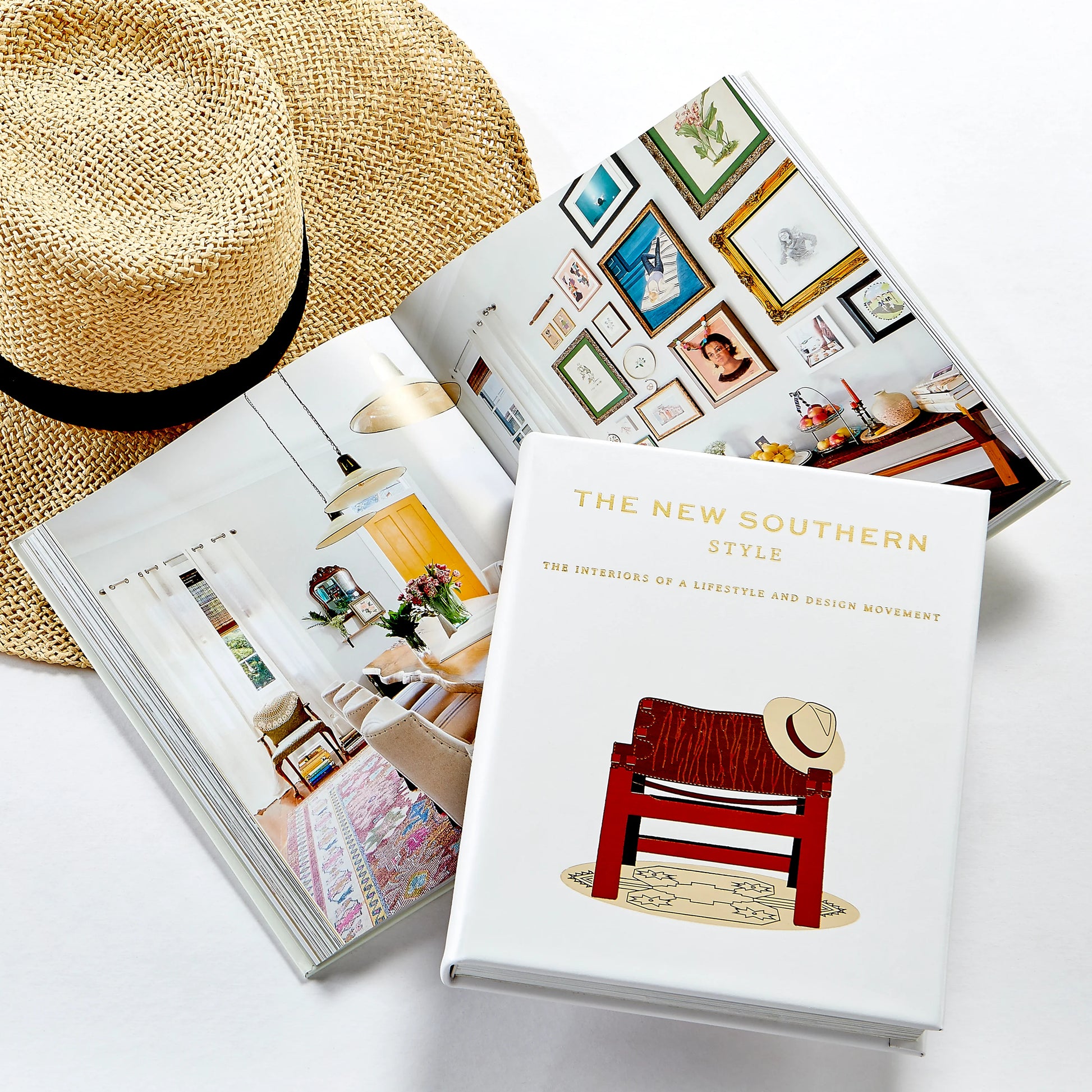 A straw hat, an open interior design book, and Graphic Image’s "The New Southern Style" are arranged on a white surface, highlighting Southern interior design.