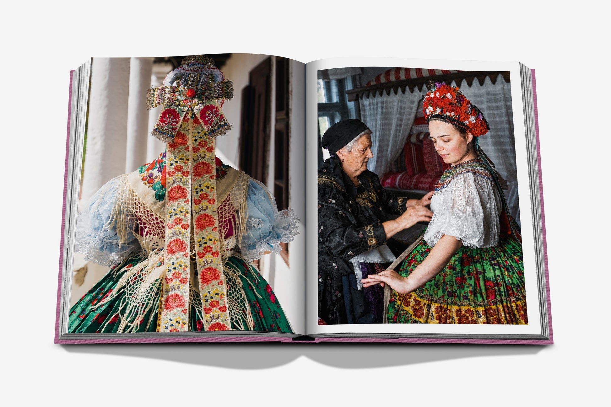 Assouline's "Budapest Gem" beautifully encapsulates Budapest's allure: one page displays a traditional costume from the back, while the adjacent page features an older woman at Buda Castle helping a younger woman adjust her similar outfit.