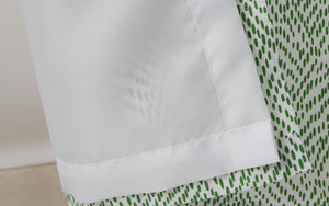 Close-up of the Matouk Shower Curtain Liner, featuring a white water-repellent surface with a green dotted pattern partially visible underneath.